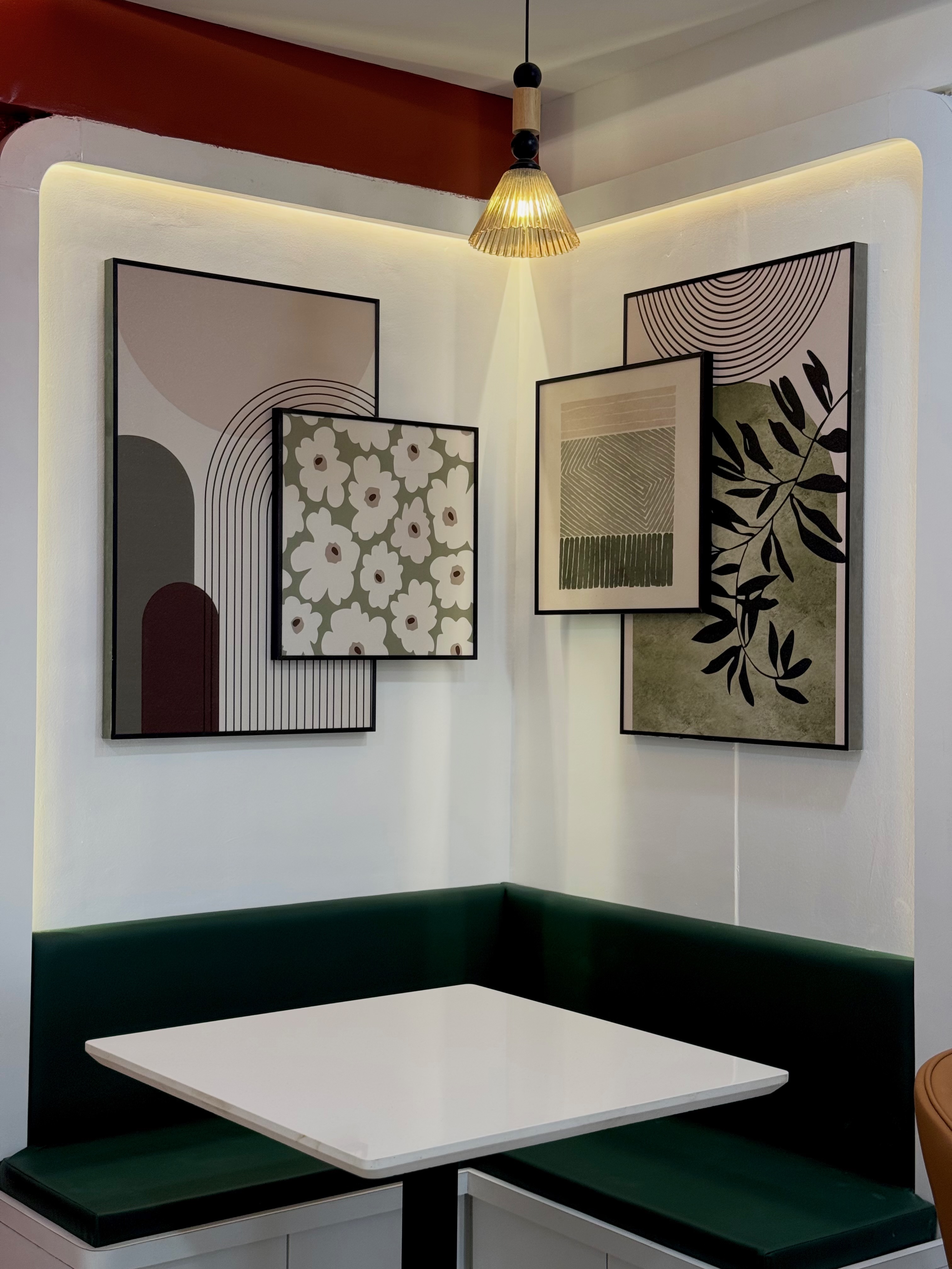 A cosy green corner bench beneath framed botanical and geometric artwork