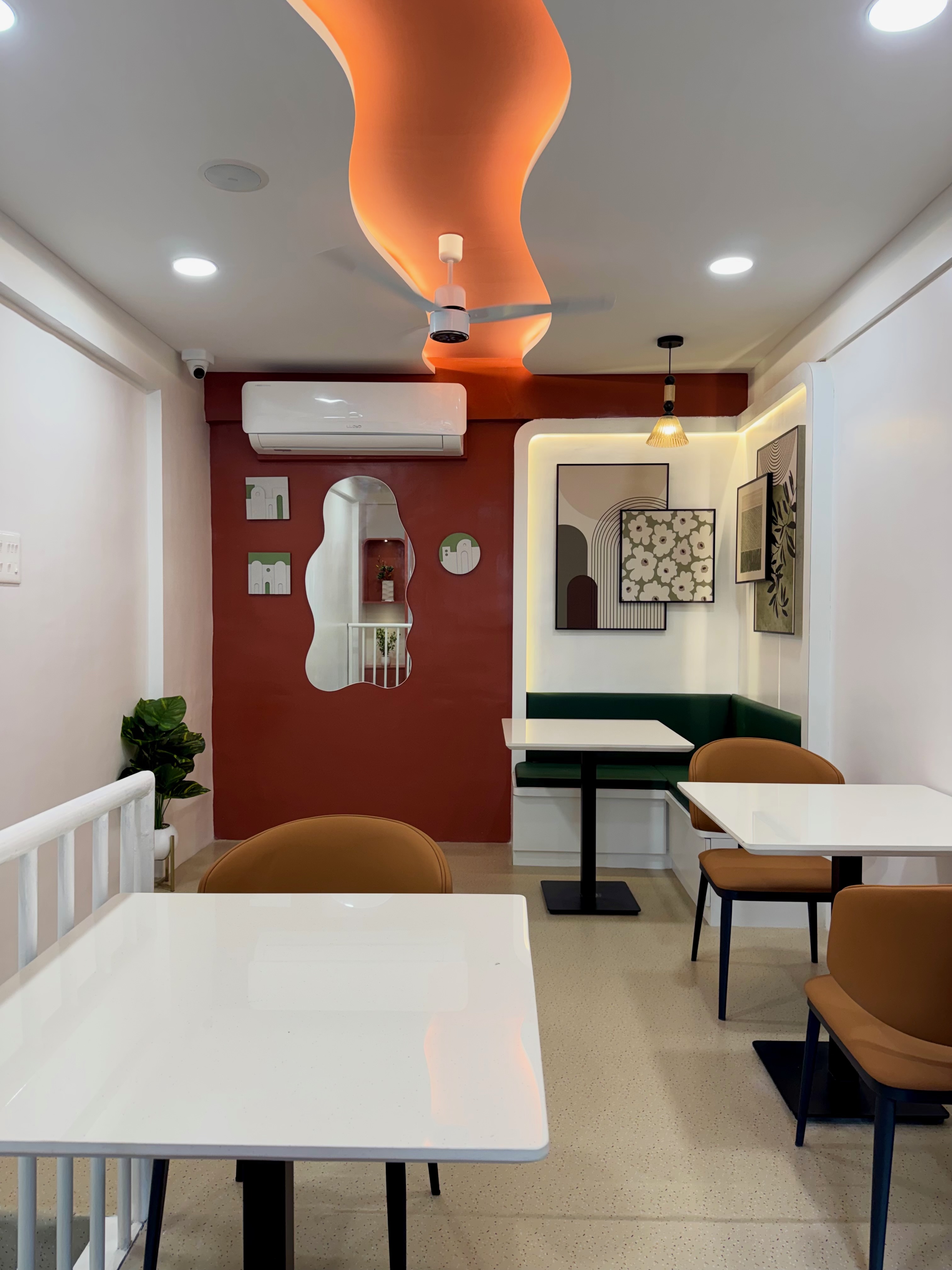 White tables, mustard chairs and a terracotta wall inside Cocuna